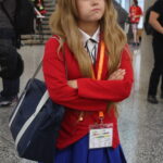 Cosplayer caracterizada como Taiga Aisaka (Toradora!), com expressão séria e postura defensiva.